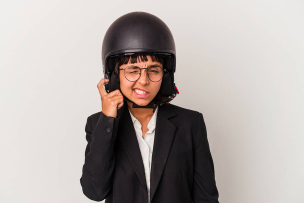Joven mujer de negocios de raza mixta con casco de moto aislado cubriendo las orejas con las manos. - Foto, imagen