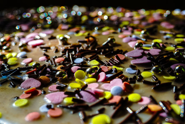 A closeup shot of colored sugar ornaments on a wooden desk - Foto, Imagen