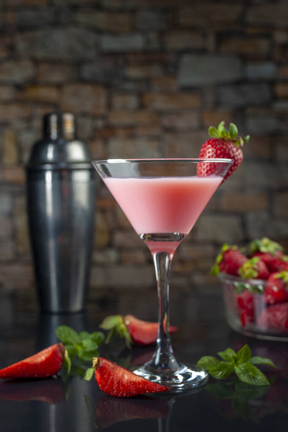 A strawberry milk cocktail with a shaking bottle and ripe berries in the background - Фото, изображение