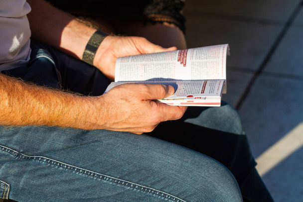 Zbliżenie rąk człowieka trzymającego książkę. Człowiek konsultujący się z drogowskazem w Barcelonie, Hiszpania. - Zdjęcie, obraz