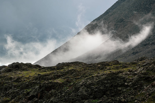 Low clouds, changeable weather in the mountains. Scenic alpine landscape with gray low clouds and sunlight. - Photo, Image
