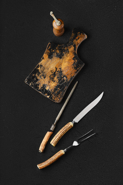 Overhead view of empty vintage wooden cutting board and knife with fork for steak - Foto, Bild