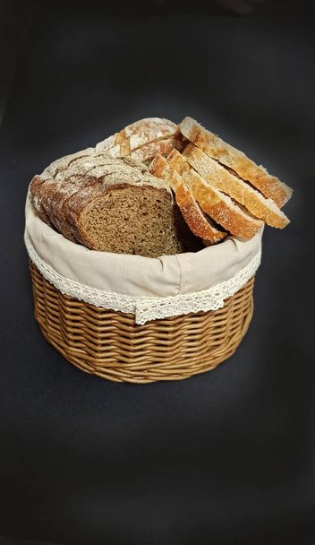 Ψάθινο καλάθι που απομονώνεται σε μαύρο φόντο. Καλάθι ψωμιού. Κομμάτια ψωμιού σε ένα καλάθι ψωμιού. Αρτοποιείο από αμπέλι. - Φωτογραφία, εικόνα
