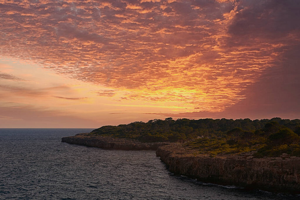 Sunset or sunrise on the coast with cliffs. Orange sky with clouds, no people - Photo, Image