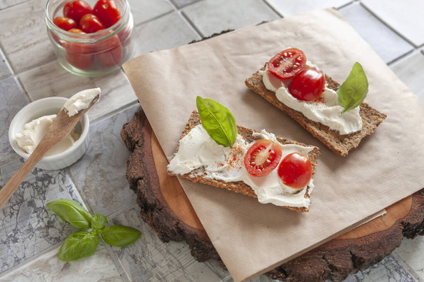 Gluten Free Organic Tomato Crackers with Lactose free Spread and fresh Tomatoes  on ceramic tile background. - Foto, Bild