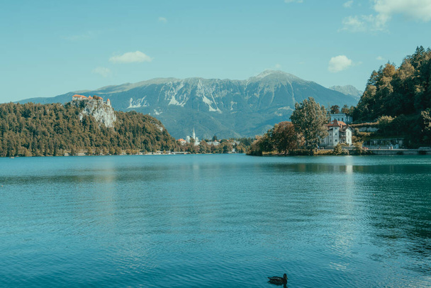 landscape on a lake surrounded by mountains and houses - Фото, изображение