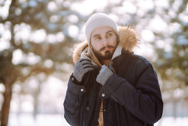 Karlı kış ormanlarında genç bir adamın portresi. Sezon, Noel, seyahat ve insanlar konsepti. - Fotoğraf, Görsel