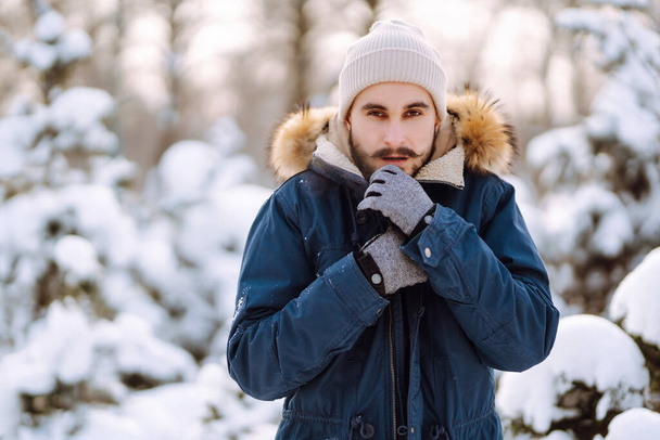Portrét mladého muže ve sněhobílém zimním lese. Sezóna, Vánoce, cestování a lidé koncept. - Fotografie, Obrázek