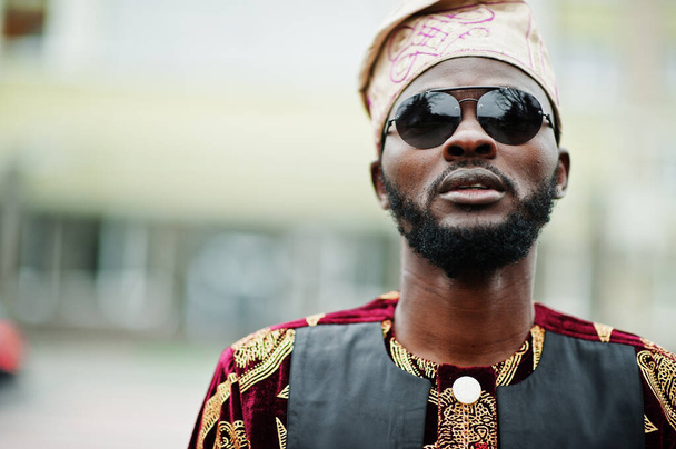 African stylish and handsome man in traditional outfit and cap standing outdoor. - Fotoğraf, Görsel