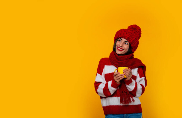 Close up photo of charming happy stylish tender woman in red winter clothes holds beverage in yellow cup in hands and relaxing - Photo, image