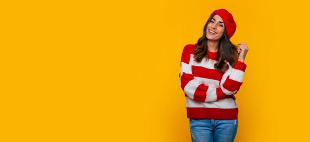 Brede banner foto van een mooie gelukkige brunette vrouw in rode baret terwijl ze droomt over iets en poseren geïsoleerd op gele achtergrond - Foto, afbeelding