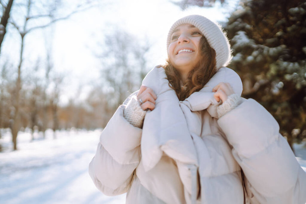 Happy woman in winter style clothes walking in the snowy park. Nature, holidays, rest, travel concept. - Фото, зображення