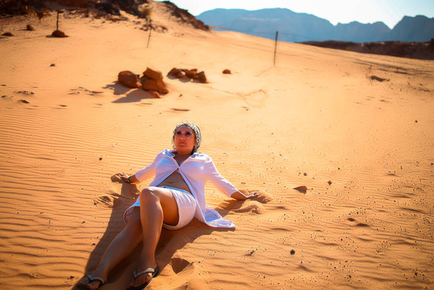 砂の上の砂漠に座って空を見上げる女性観光客が - 写真・画像