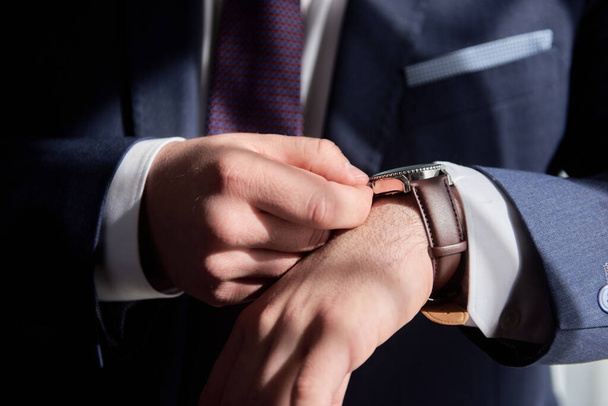 Close up of watches on male hand indoors, copy space. Man in suit checking time from luxury wristwatches. Watch on hand. Groom wedding preparation - Photo, image