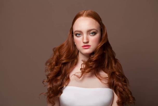 Gyönyörű fiatal nő vörös hajjal. Piros hajú modell barna alapon - Fotó, kép
