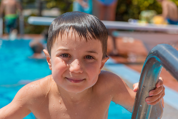 Улыбающийся мальчик (5-6 лет) на лестнице бассейна
. - Фото, изображение