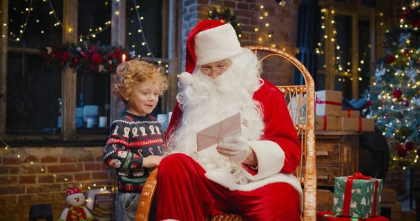 Close up portrait of Santa Claus with little boy playing together. Merry Christmas and happy holidays. New years celebration - Foto, Imagem