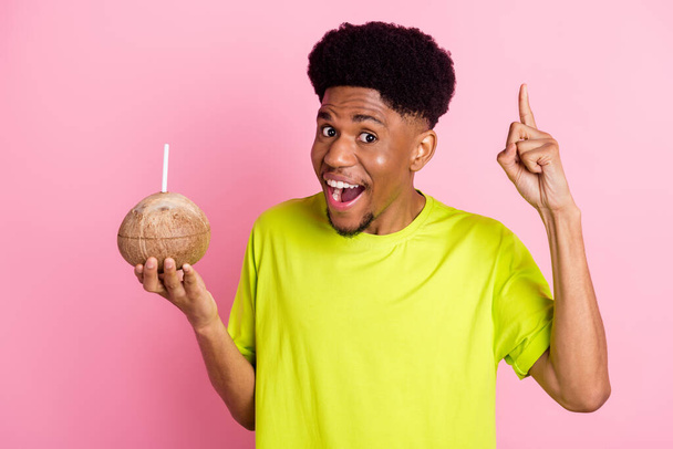 Foto van vrolijke jonge Afro-Amerikaanse man houden hand kokosnoot drank idee geïsoleerd op roze kleur achtergrond - Foto, afbeelding
