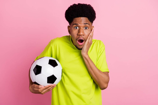 Photo of young african guy amazed shocked surprised hand touch cheek hold soccer ball goal isolated over pink color background - Foto, afbeelding