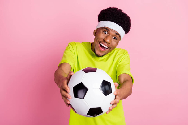 Portrait of attractive cheerful guy holding giving you pass soccer ball isolated over pink pastel color background - 写真・画像