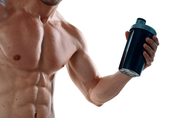 a man an athlete with a pumped-up body drinks from a bottle - Foto, imagen