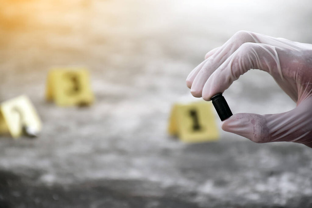 Forensiker halten Handfeuerwaffen oder Pistolenkugeln in der Hand, die wichtige physische Beweise sind, während sie am Tatort Beweise sammeln. Weiche und selektive Fokussierung. - Foto, Bild