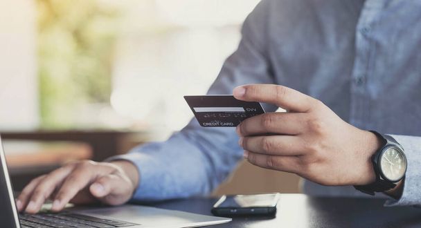 Çevrimiçi ödeme, adamın elleri kredi kartı tutuyor ve bilgisayarla online alışveriş yapıyor. Siber Pazartesi Onaylaması - Fotoğraf, Görsel