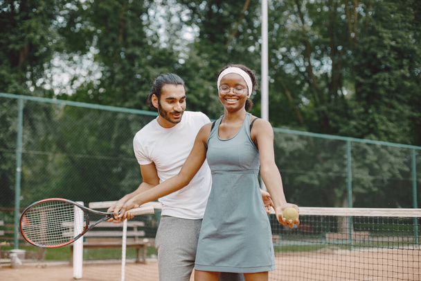Man teaching a woman how to play tennis - Fotografie, Obrázek