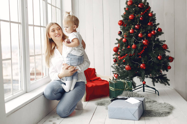 Mother with little daughter sitting by the Christmas tree and having fun. - Foto, Imagem