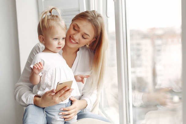 Mother and little daughter spend time together sitting on the windowsill. - Photo, Image