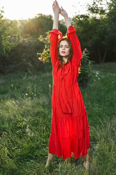 aantrekkelijke vrouw in rode jurk buiten in vrijheid veld - Foto, afbeelding
