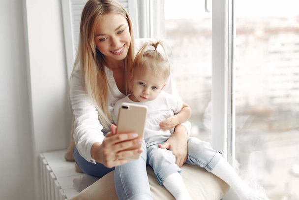 Mother and little daughter spend time together sitting on the windowsill. - 写真・画像
