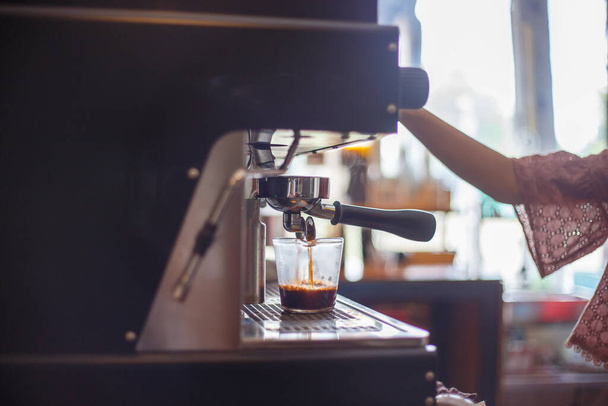 カフェでコーヒーを作る女性バリスタのクローズアップショット - 写真・画像