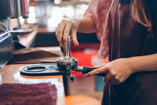 Close-up shot of a female barista holding a portafilter in a cafe - Photo, Image