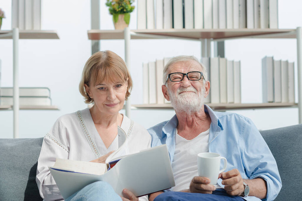 Elderly senior family couple in casual outfit embracing and using smart tablet with smile happy and romantic emotion in living room. - Photo, Image