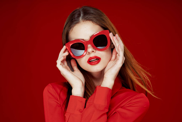 beautiful woman wearing sunglasses red shirt makeup isolated background - Фото, изображение
