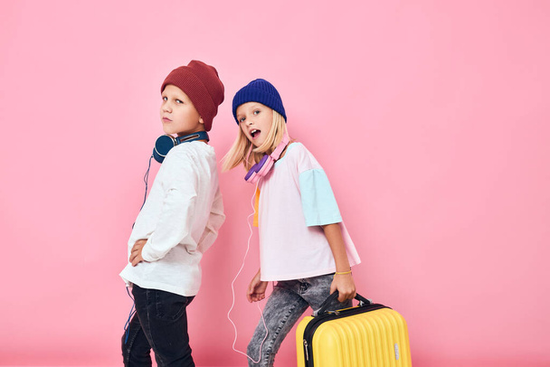 Portrait of a girl and a boy stylish clothes suitcase headphones isolated background - Foto, immagini