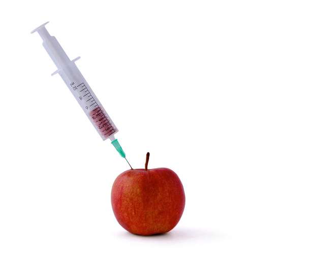 Medical syringe witn pills and red apple lying  the desk, isolated on white background - Photo, Image