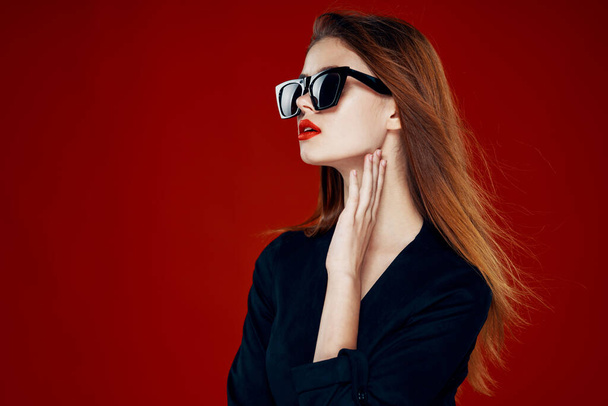 cheerful fashionable woman wearing sunglasses red lips posing red background - Foto, immagini