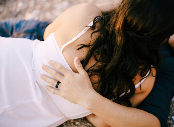 Homem e mulher abraçando enquanto deitados no caminho de cascalho no parque - Foto, Imagem