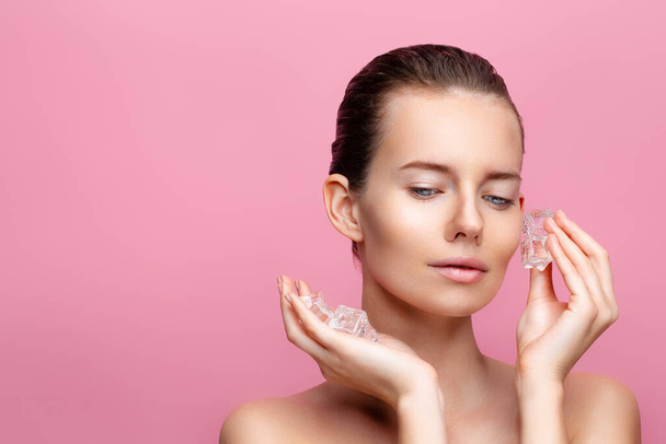 Beauty caucasian woman with healthy clean fresh skin applies Ice cubes on face. Skincare concept  - Fotó, kép