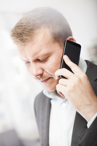 Empresario frunciendo el ceño ante una llamada en su móvil
 - Foto, imagen
