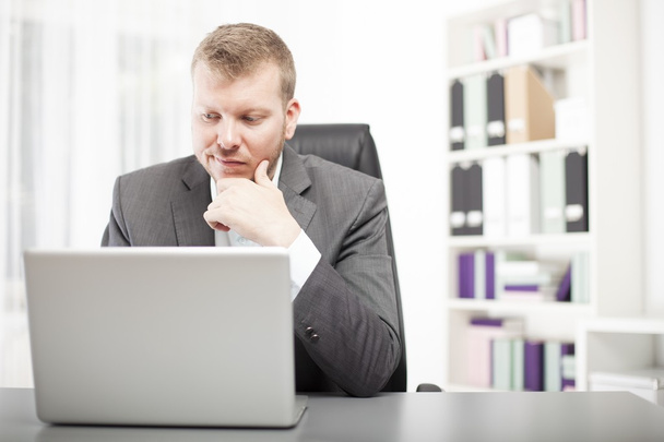 Man looking at his laptop with a wry expression - Photo, Image