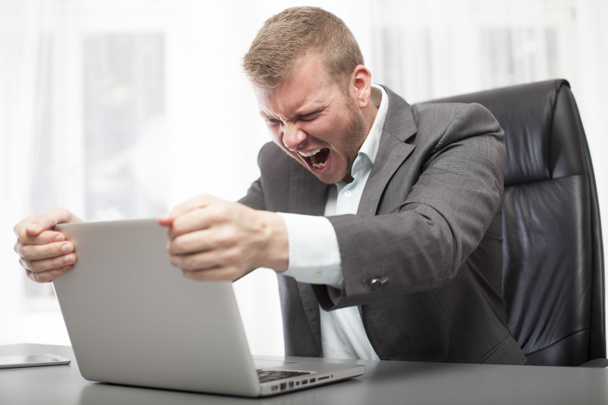 Злой бизнесмен трясет ноутбуком
 - Фото, изображение