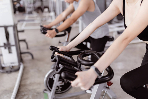 koncepcja ćwiczeń Dwaj uczestnicy klubu sportowego grający na rowerze treningowym do wykonywania cardio obok siebie. - Zdjęcie, obraz