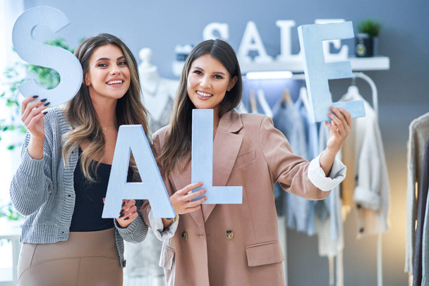 Дві дівчини на шопінгу тримають знак продажу відсотків
. - Фото, зображення