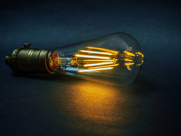 Elongated LED filament light bulb on the background of dark background. Close-up - Foto, afbeelding