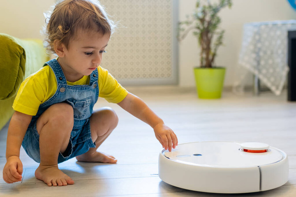 little boy 2 years ago starts a robot vacuum cleaner - Foto, immagini