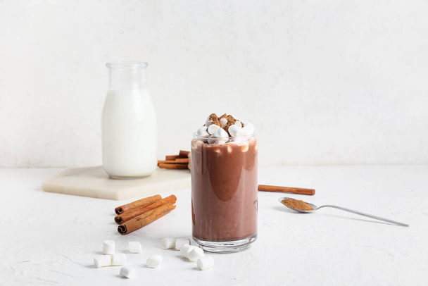Glass of tasty coffee with cinnamon and marshmallows on white background - Zdjęcie, obraz