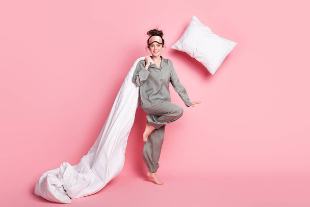 Full length body size view of pretty funny cheerful girl throwing pillow having fun isolated over pink pastel color background - 写真・画像